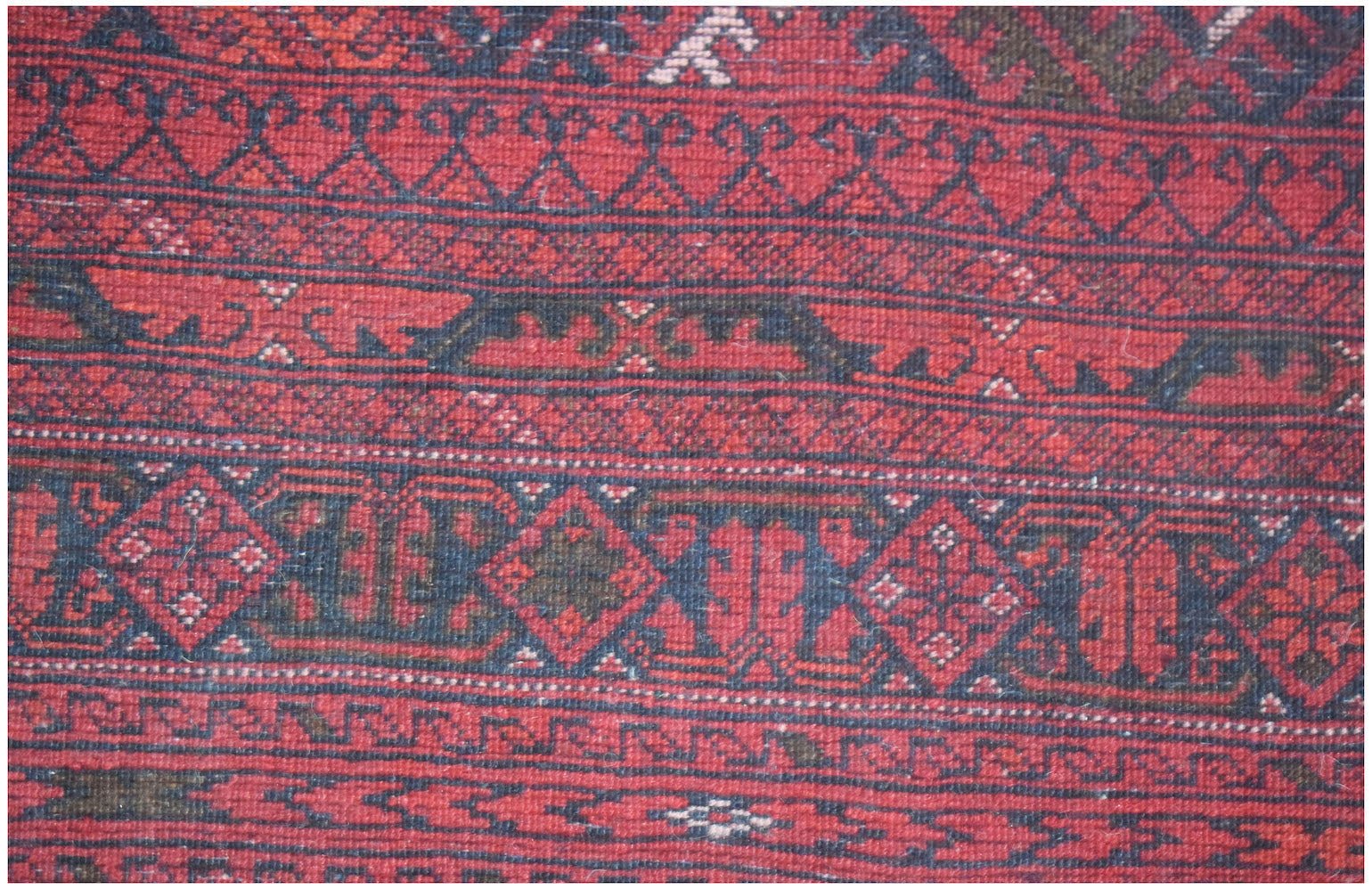 A vintage handmade Afghan Turkmen rug featuring traditional red and dark blue geometric patterns.