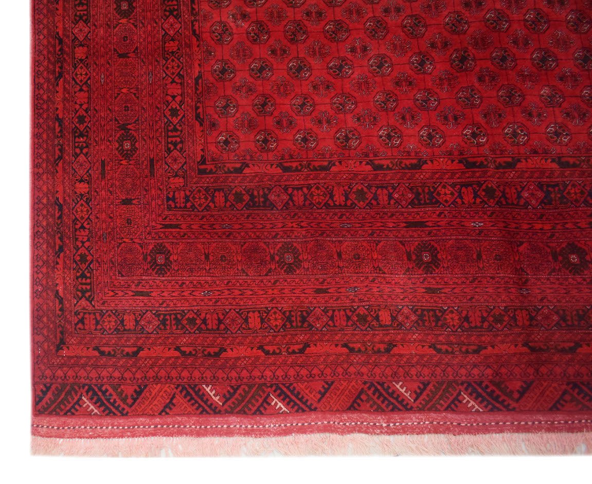 A vintage Afghan Turkmen rug featuring a deep red field with repeating elephant foot motifs.