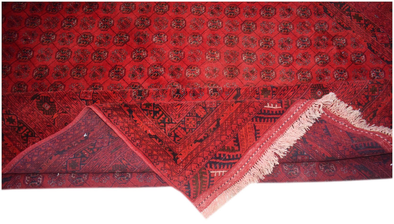 A vintage handmade Afghan Turkmen rug featuring a red field with repeating elephant foot motifs.