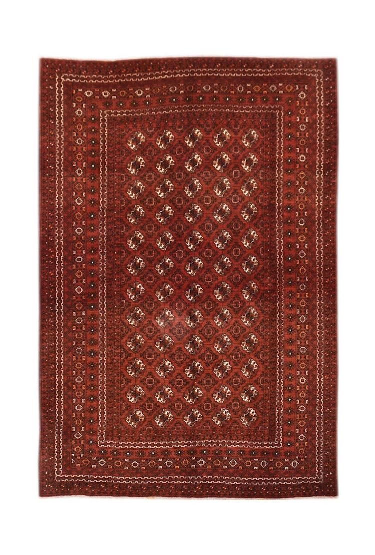 A vintage handmade Afghan Turkmen rug featuring a repeating geometric elephant foot motif in red.