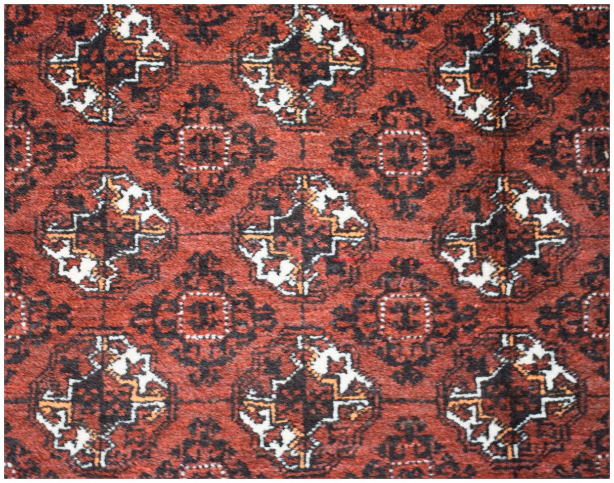 A vintage Afghan Turkmen rug featuring a repeating geometric elephant foot motif in red and black.