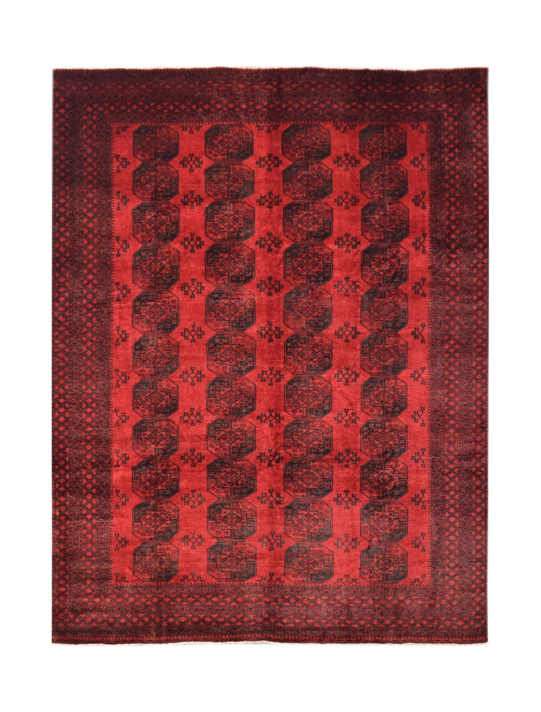 A vintage Afghan Turkmen rug featuring a repeating dark red elephant foot motif on a red field.