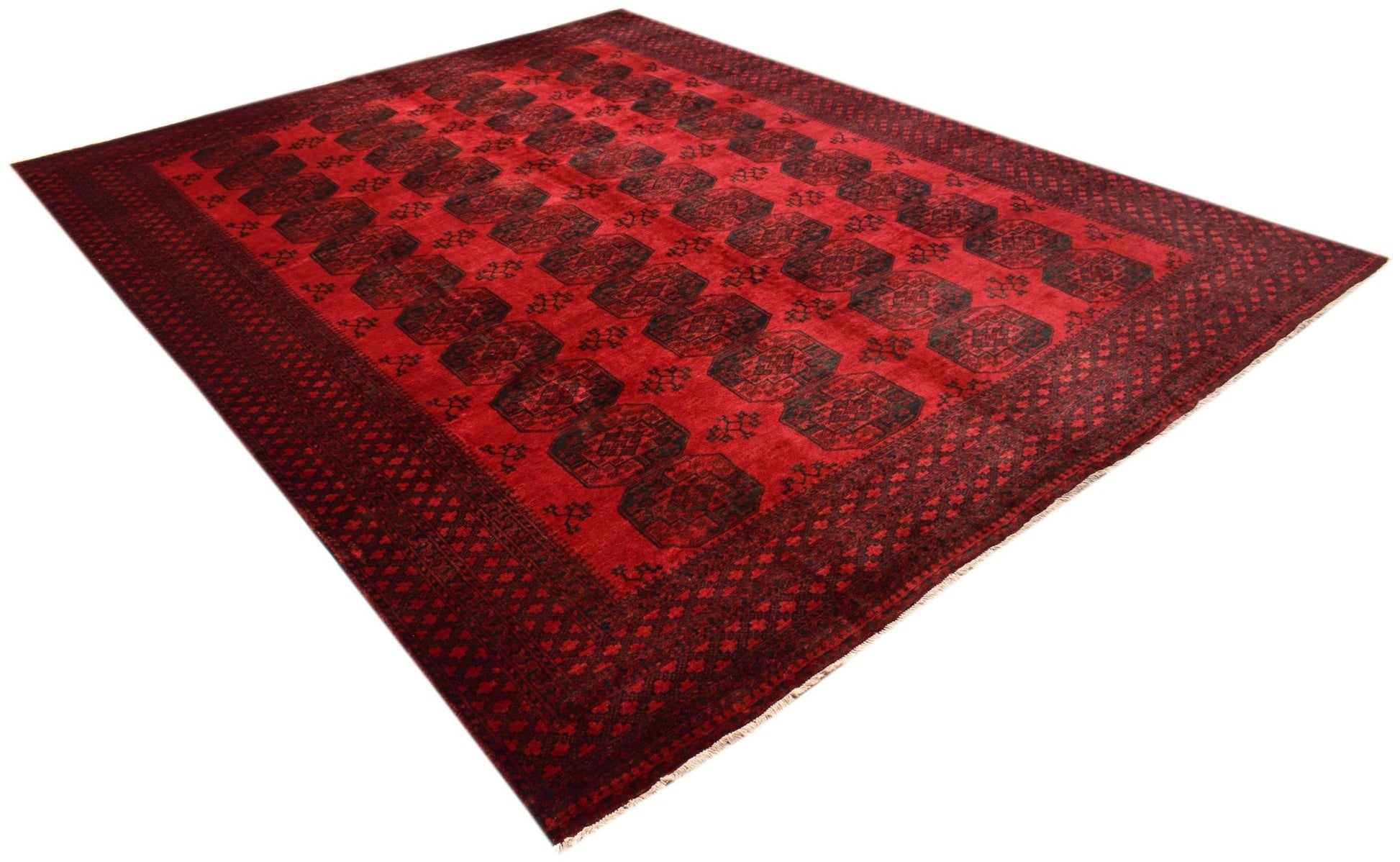 A vintage handmade Afghan Turkmen rug featuring a repeating dark red elephant foot motif.