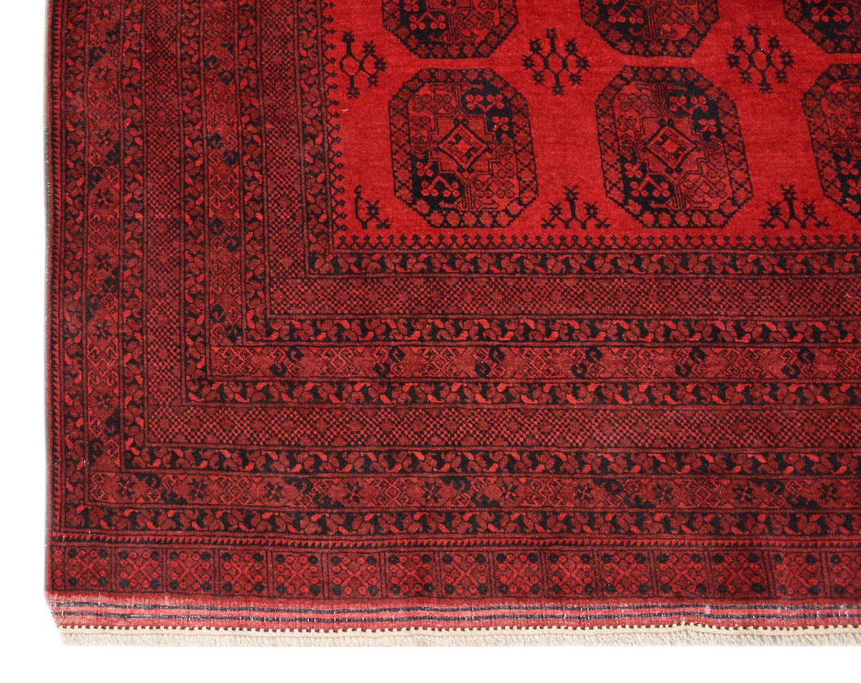 A vintage handmade Afghan Turkmen rug featuring a red field with black elephant foot motifs.