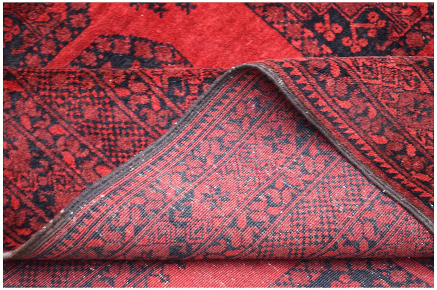 A vintage Afghan Turkmen rug featuring a red and black geometric elephant foot pattern.