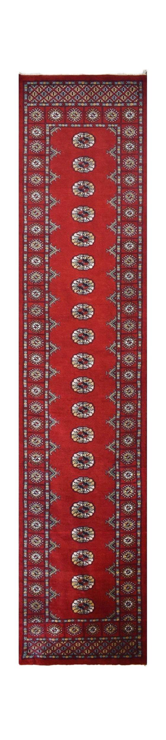 A handmade red wool runner rug featuring a repeating pattern of dark Princess Bokhara motifs.