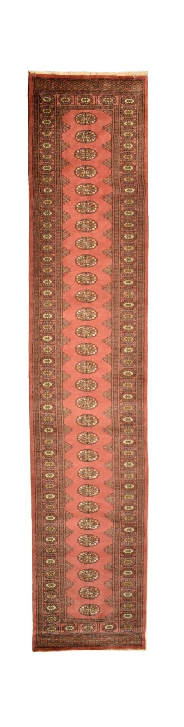 A handmade wool runner rug featuring a salmon pink field with repeating oval Bokhara motifs.