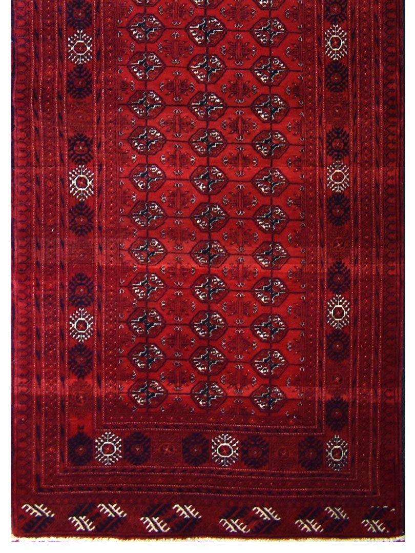 A vintage Afghan Turkmen runner rug featuring repeating geometric guls on a deep red wool field.