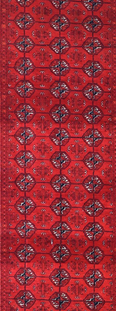 A vintage Afghan Turkmen runner rug featuring a repeating geometric pattern in deep red tones.