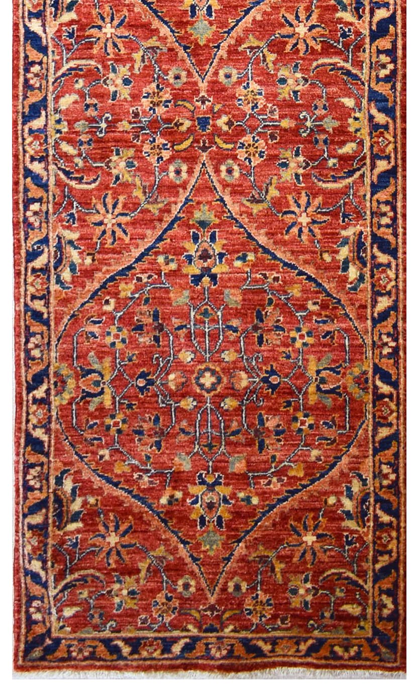 Handmade Afghan Chobi runner rug featuring a central diamond medallion on a red floral field.
