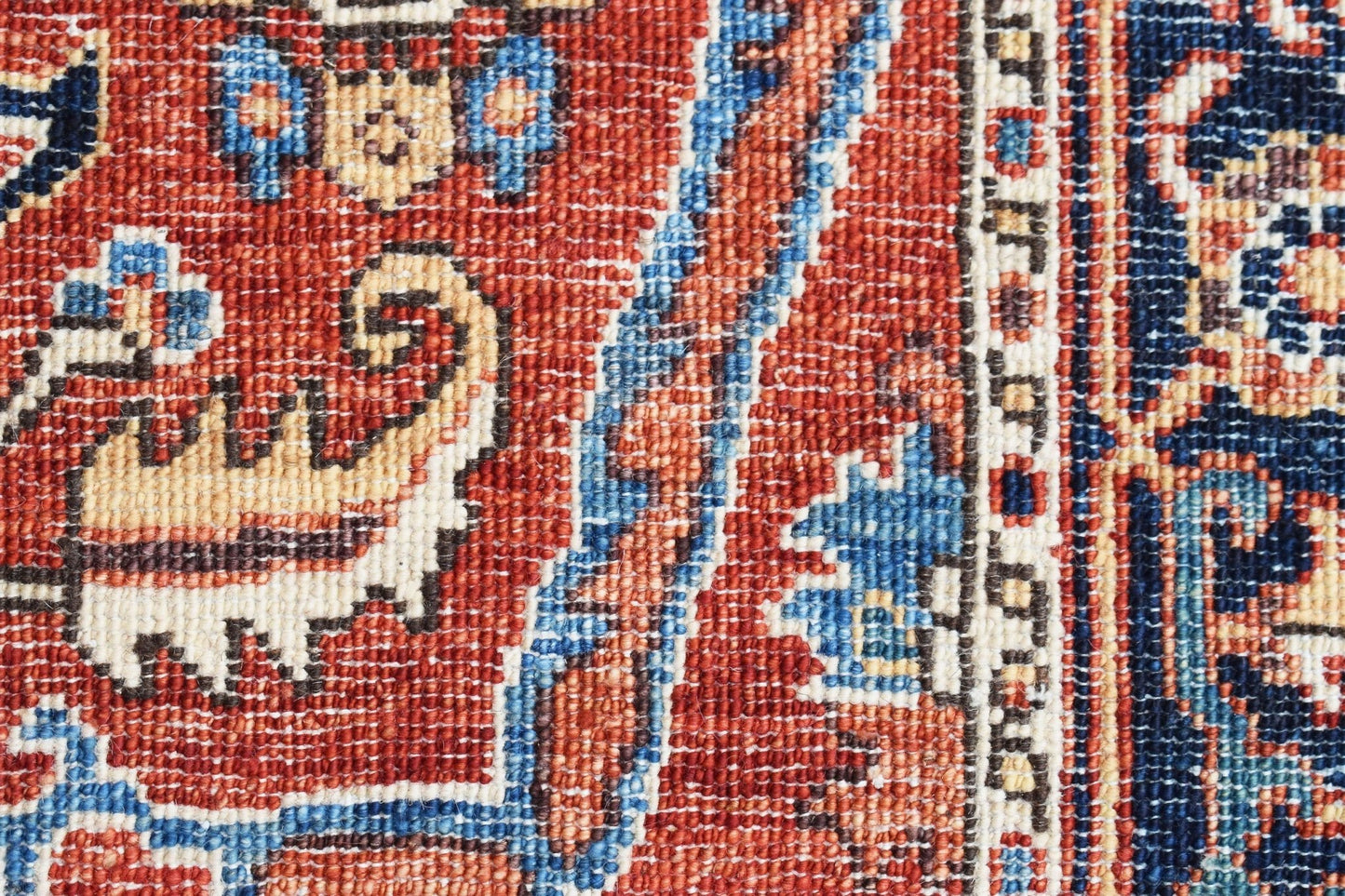A close-up of an Afghan Chobi runner featuring intricate floral patterns in red, blue, and cream.