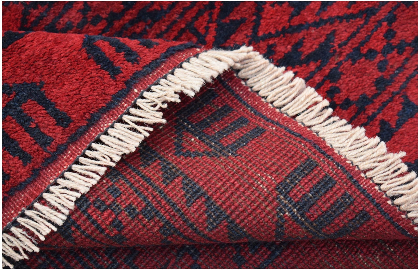 A close-up of a handmade Afghan Turkmen rug featuring a red and black geometric elephant foot motif.