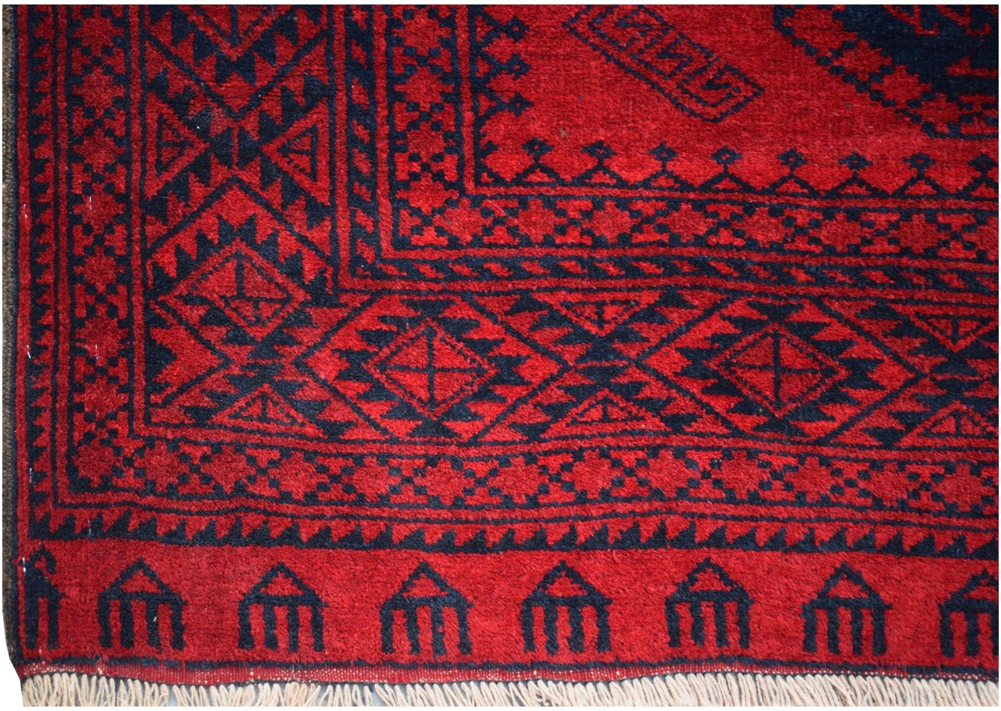 A vintage Afghan Turkmen rug featuring a deep red background with black geometric elephant foot motifs.