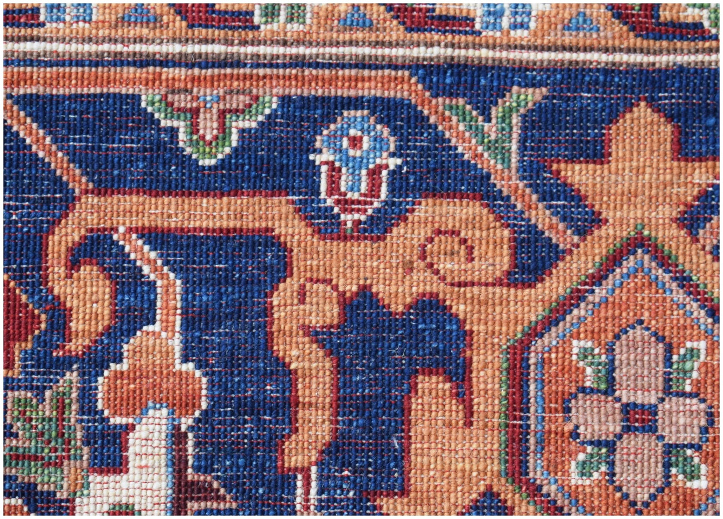 A close-up of a handwoven Afghan Chobi rug featuring intricate floral patterns in blue and orange.