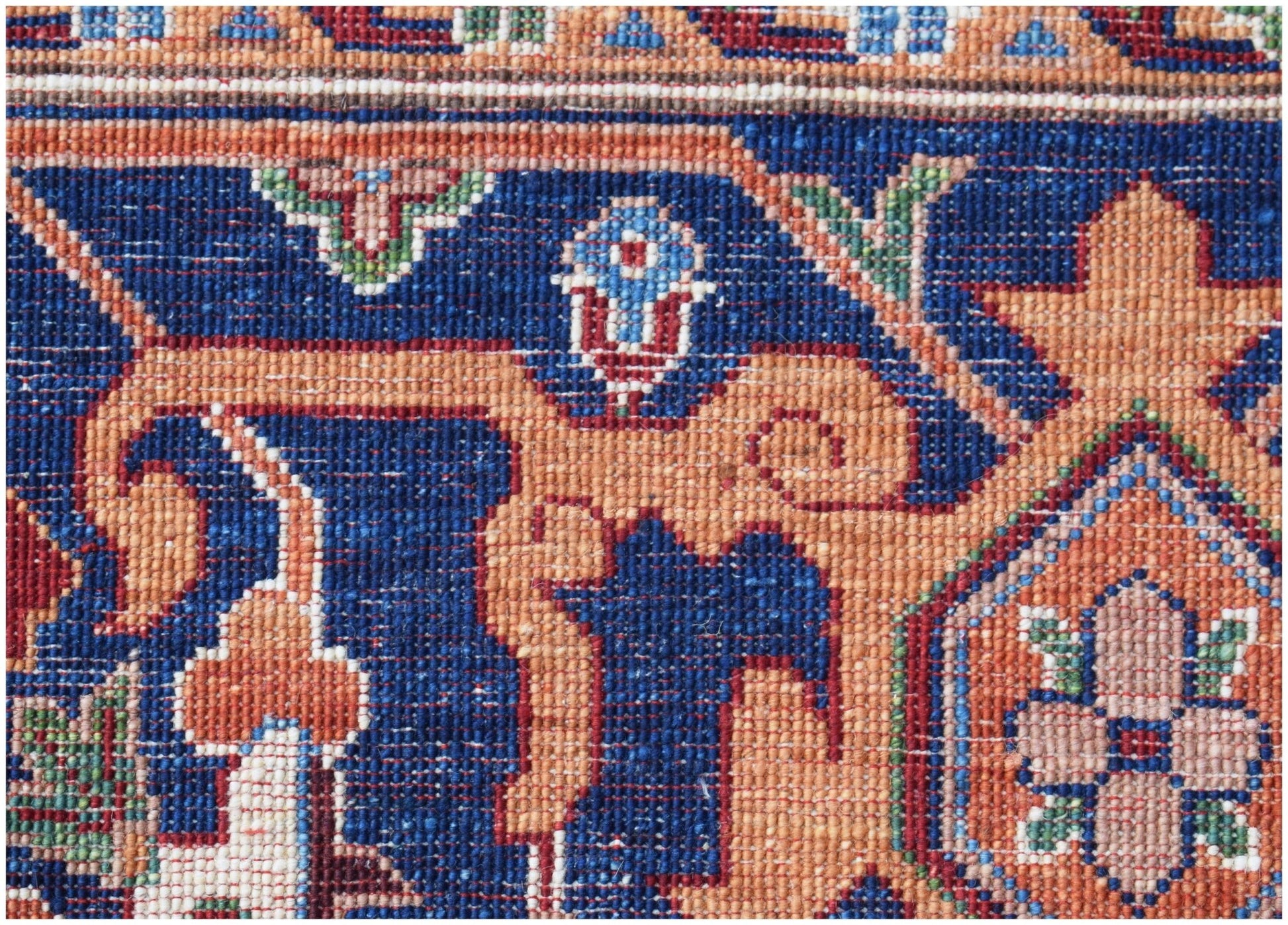 A close-up of a handwoven Afghan Chobi rug featuring intricate floral patterns in blue and orange.