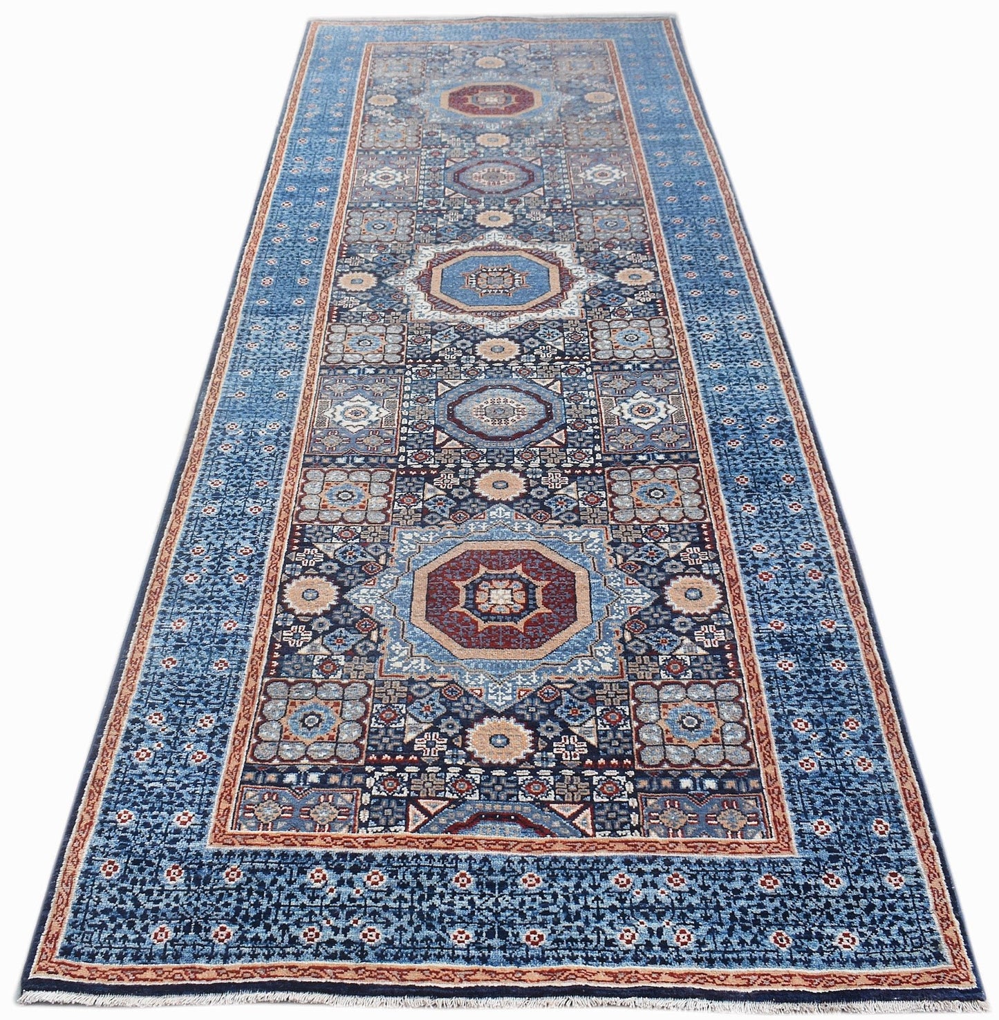 A handmade Afghan Chobi runner rug featuring intricate geometric medallions in blue and red tones.
