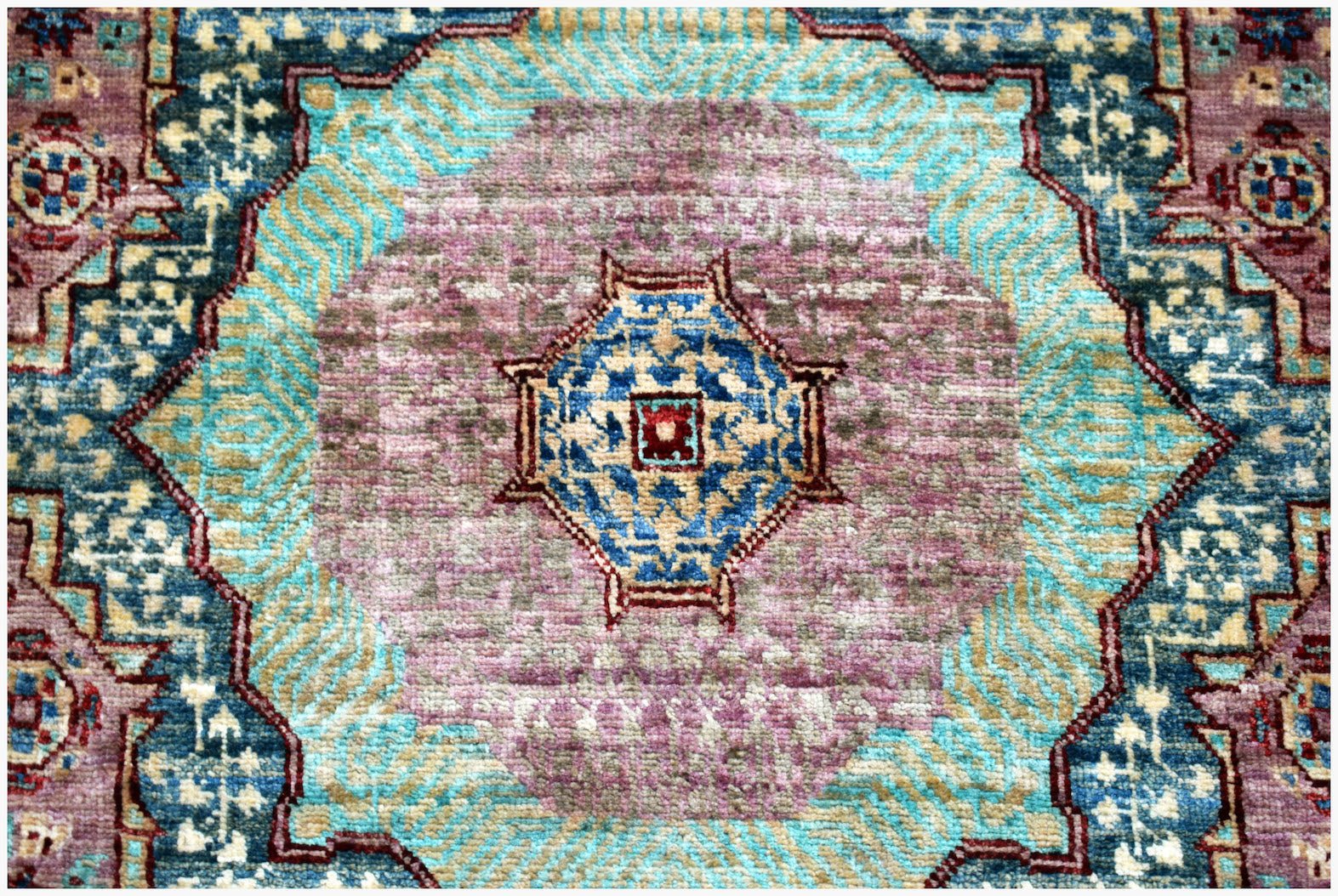 A handmade Afghan Chobi runner featuring a central geometric medallion in blue, purple, and gold.