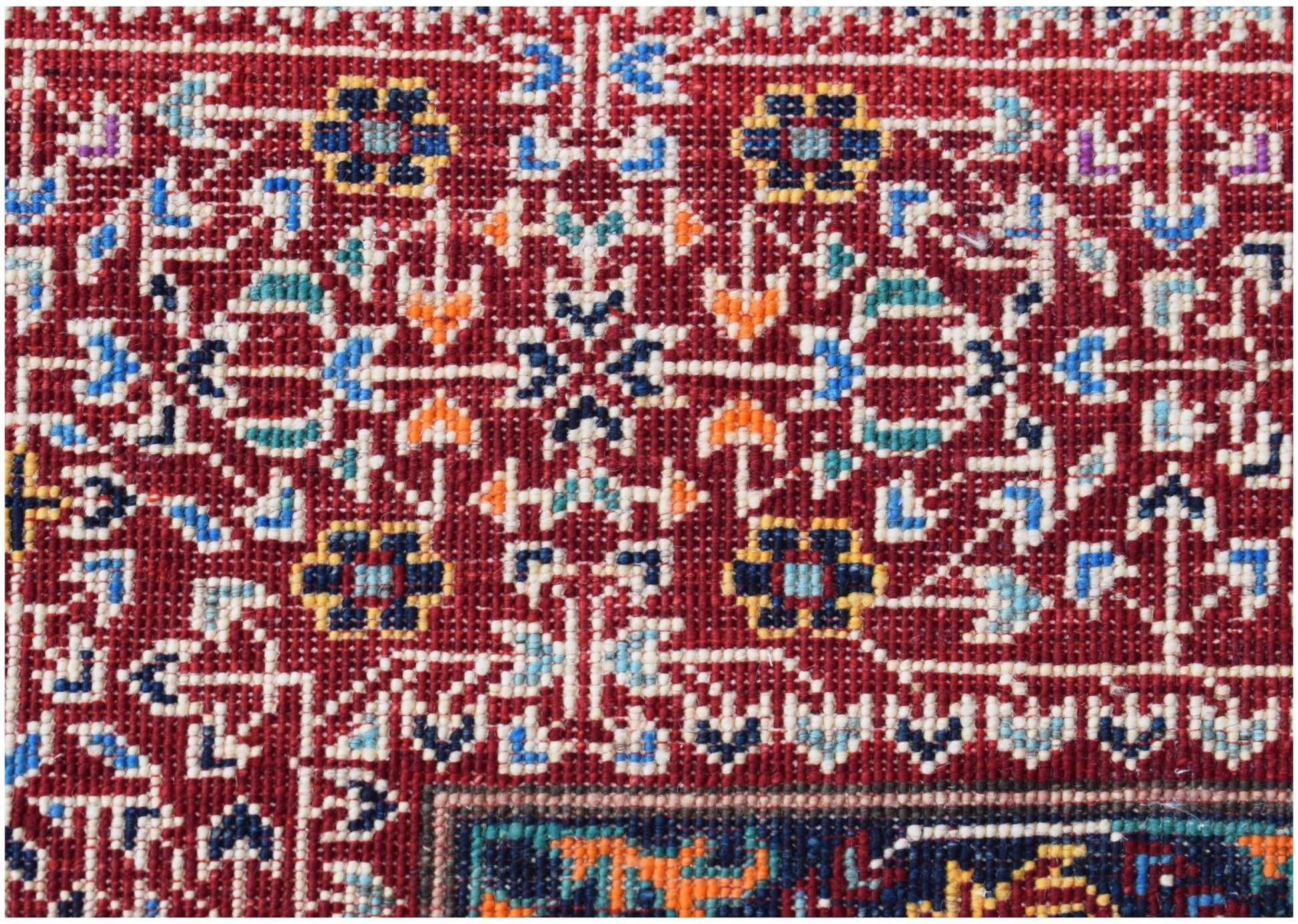 A close-up of a handmade Afghan Chobi rug featuring intricate geometric floral patterns in red.