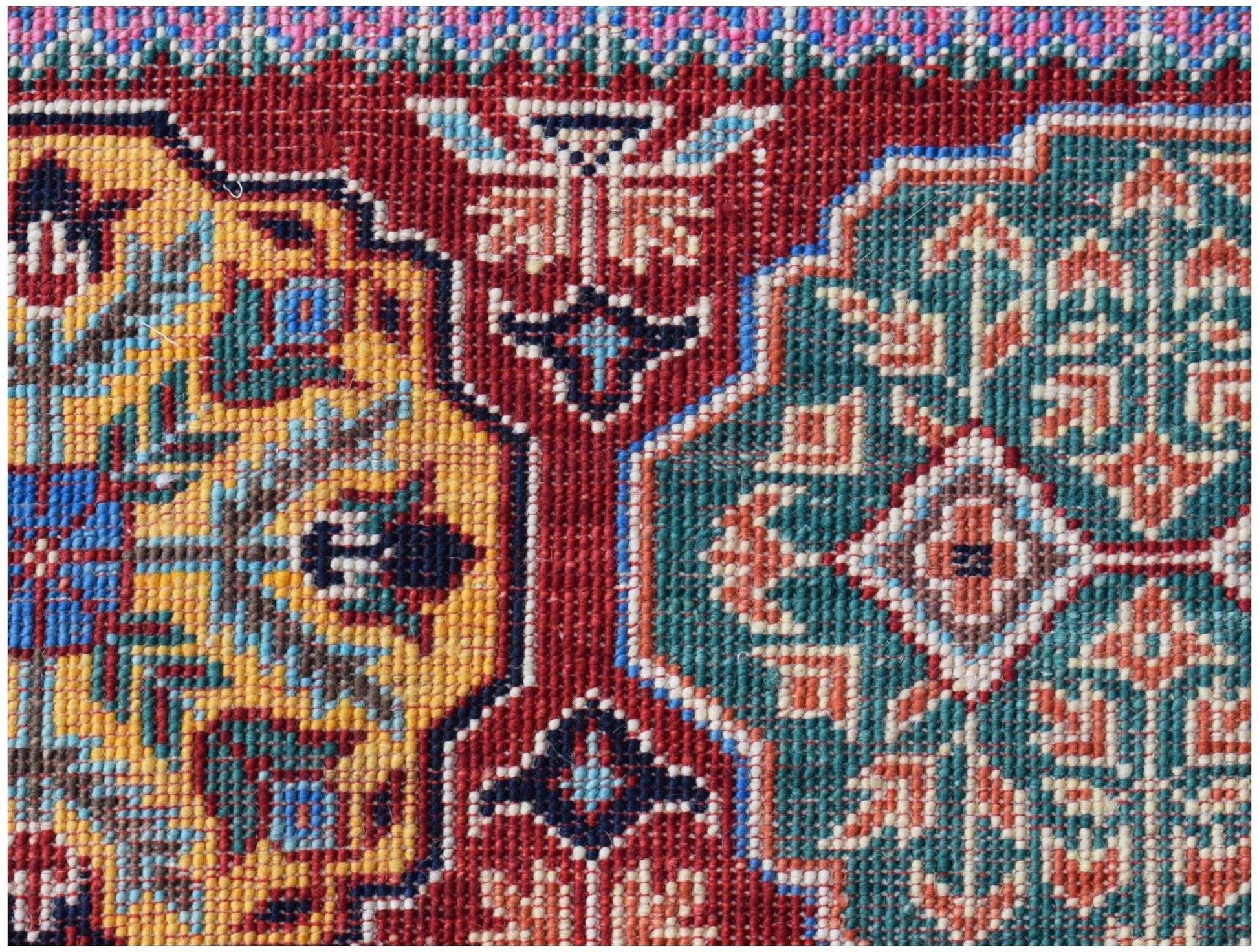 A close-up of a handwoven Afghan Chobi rug featuring intricate geometric medallions in wool.