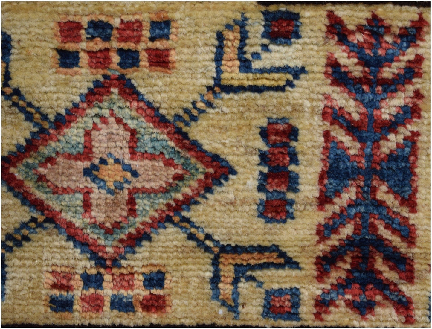 A close-up of an Afghan Super Kazakh rug featuring a geometric diamond pattern in red and blue.