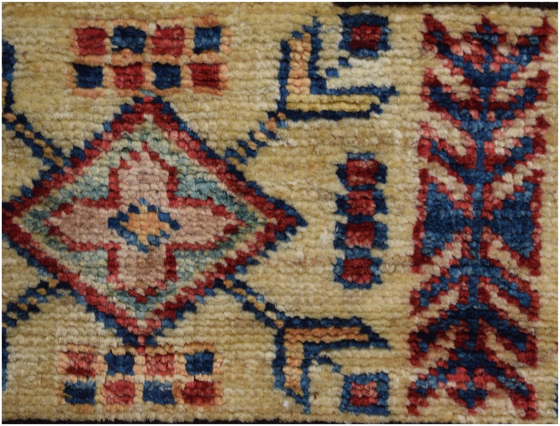 A close-up of an Afghan Super Kazakh rug featuring a geometric diamond pattern in red and blue.