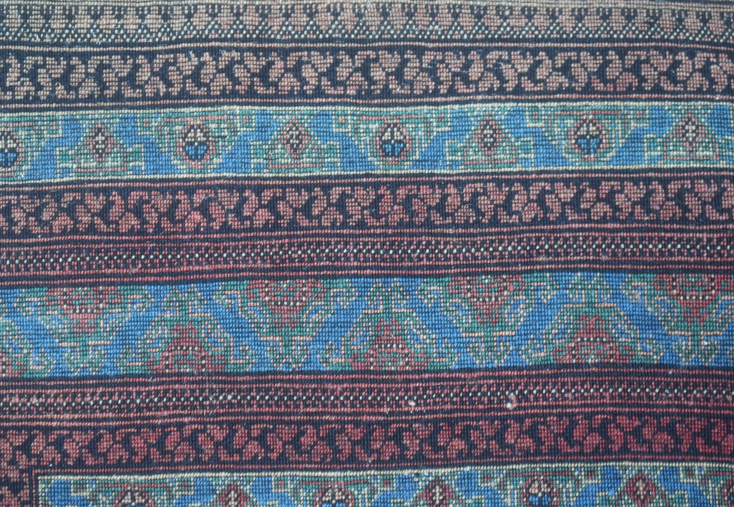 A close-up of a vintage Afghan Turkmen rug featuring intricate geometric patterns in wool.