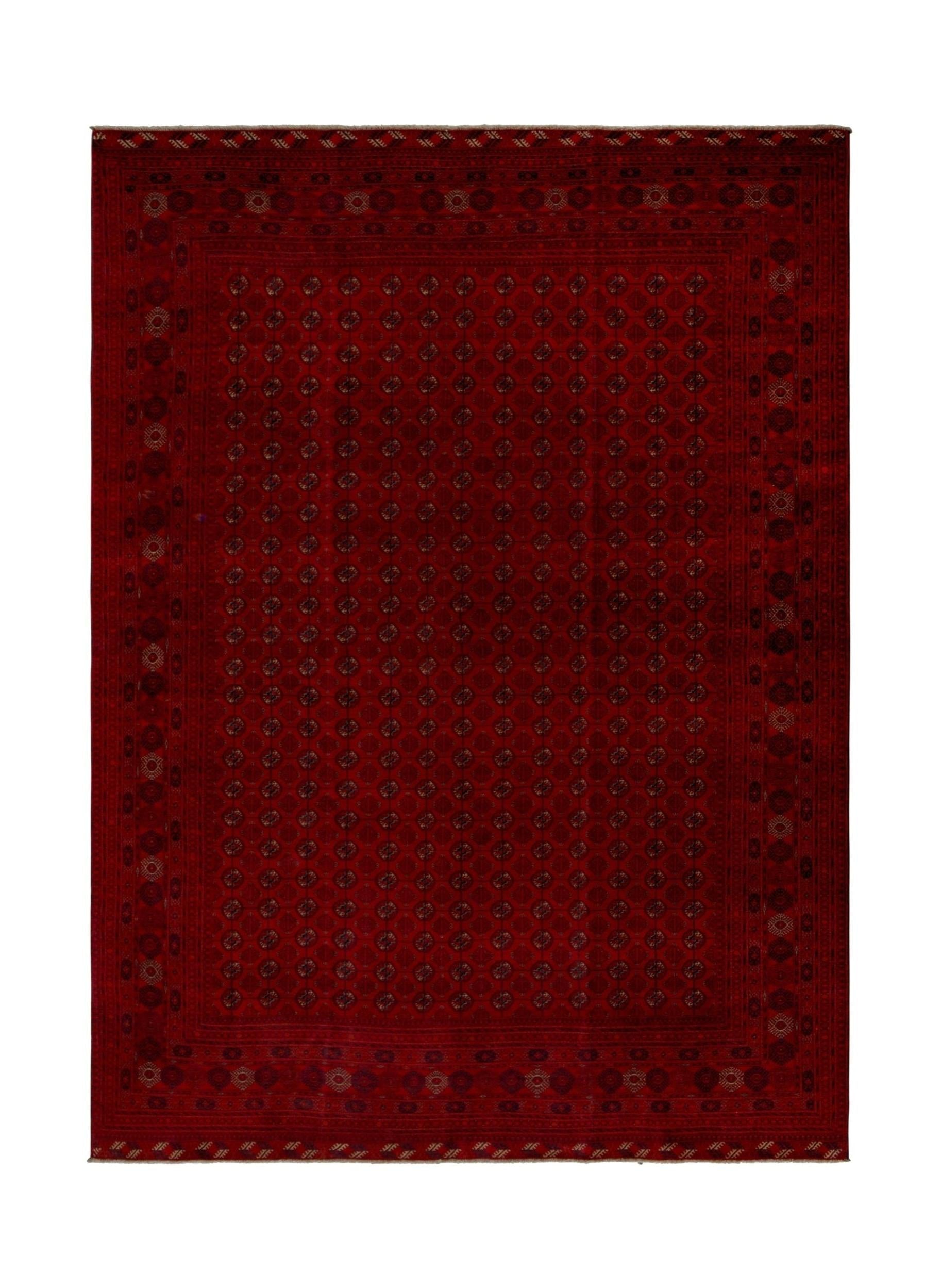 A rectangular handmade Afghan Turkmen rug featuring a deep red field with repeating geometric motifs.