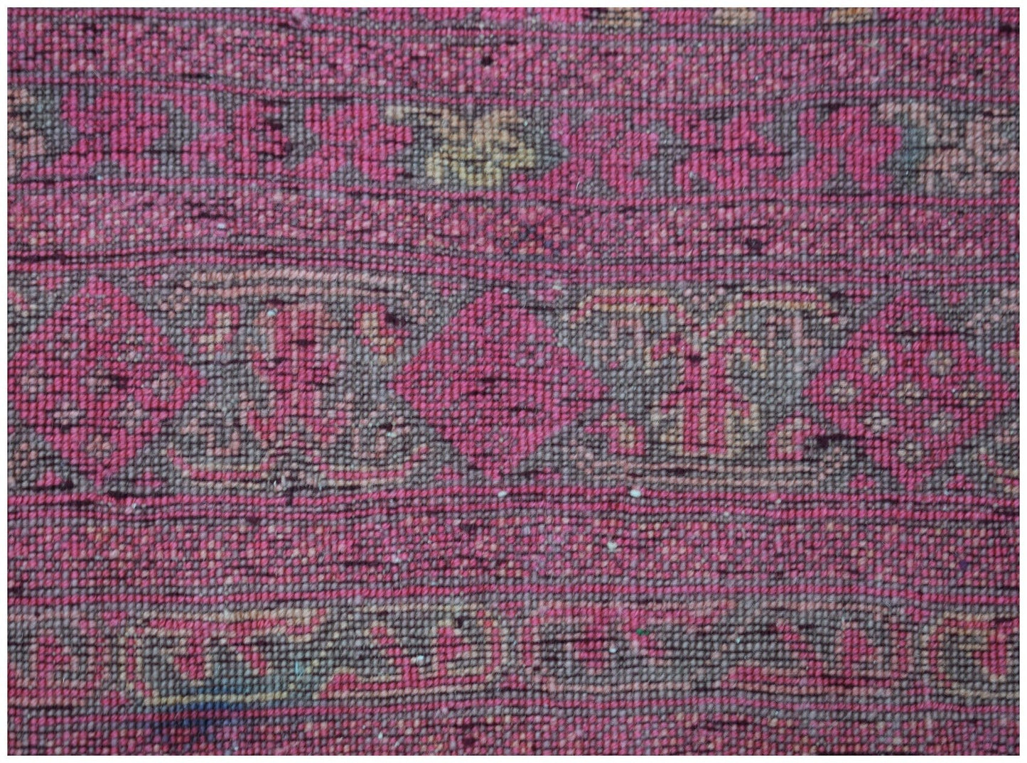 A close-up of a vintage Afghan Turkmen rug featuring intricate geometric patterns in pink and brown.