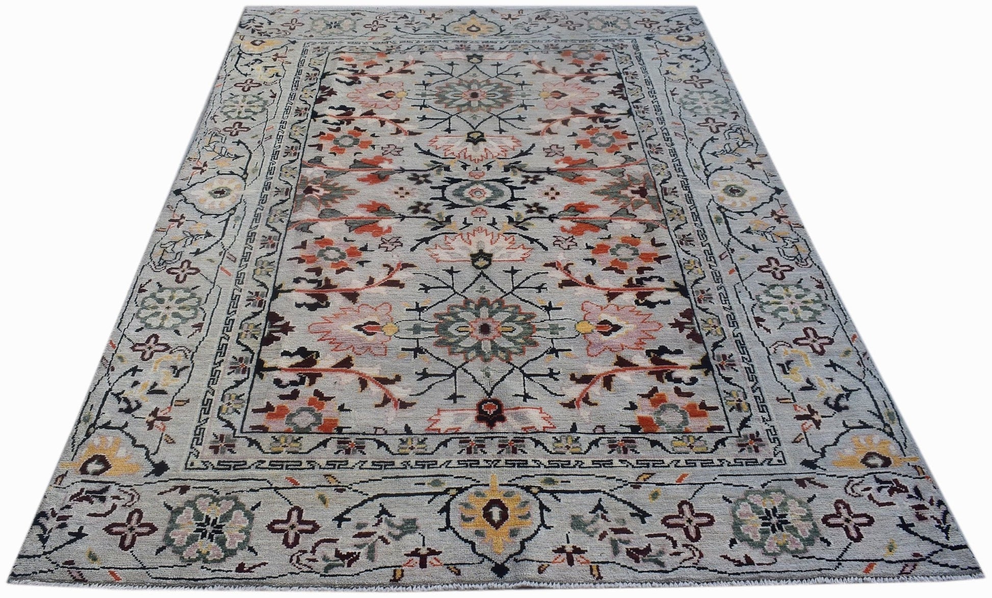 A hand-knotted wool rug featuring a light blue background with floral and geometric patterns.