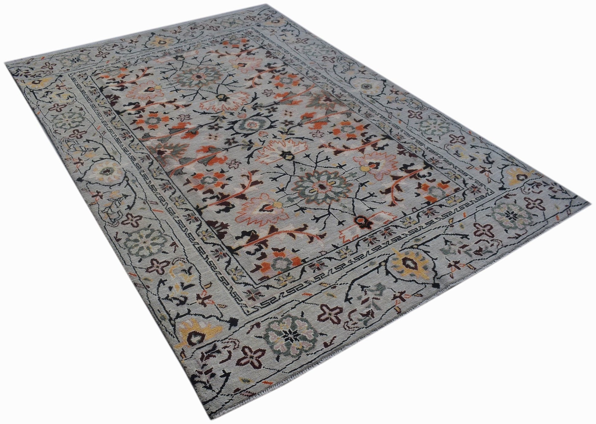 A hand-knotted wool rug featuring a grey background with intricate floral and geometric patterns.
