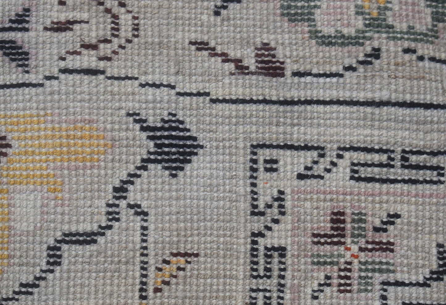 A close-up view of a hand-knotted wool rug featuring geometric patterns in muted earth tones.