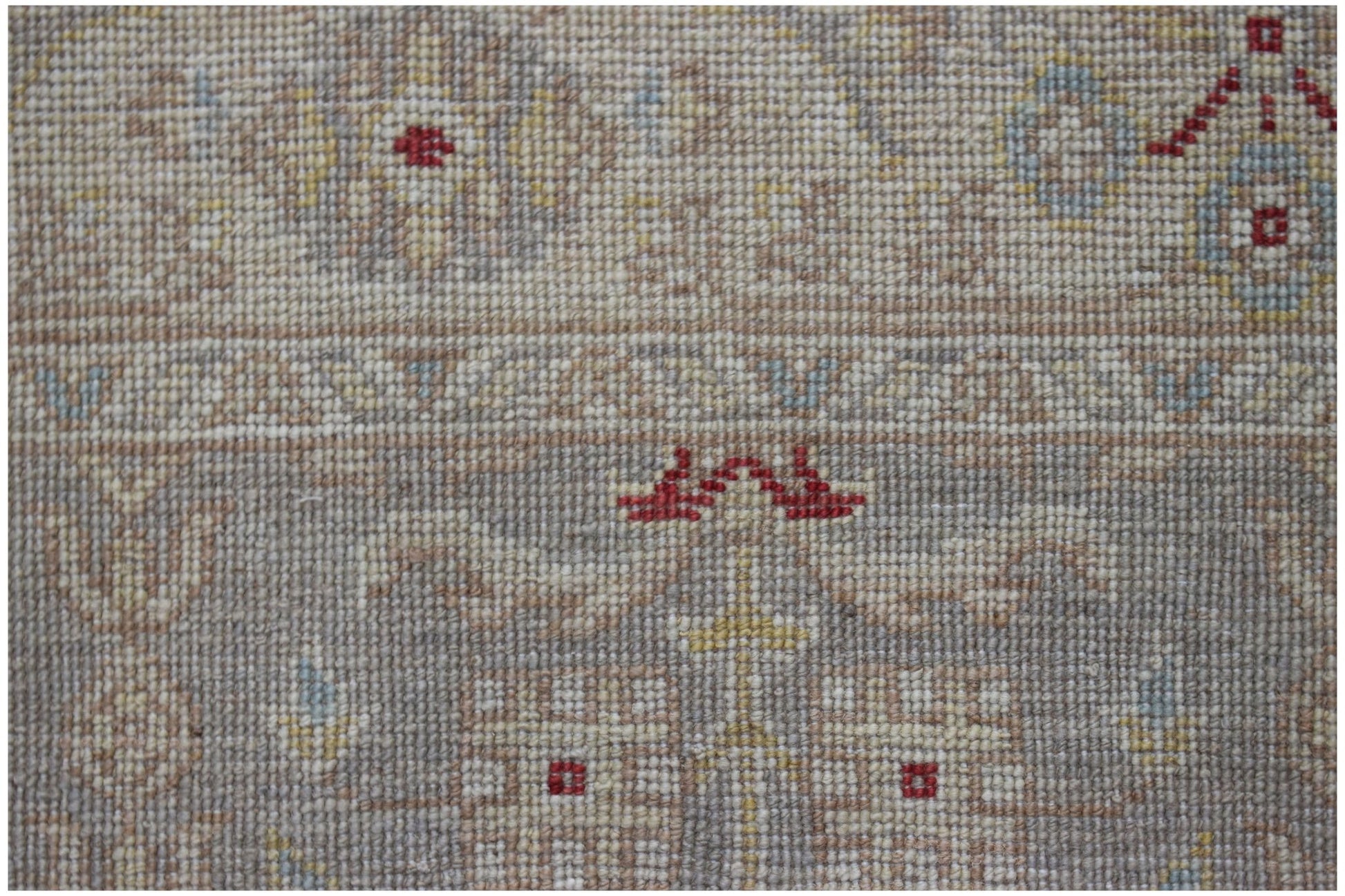 A close-up of a handmade Afghan Chobi runner featuring intricate floral patterns in muted tones.