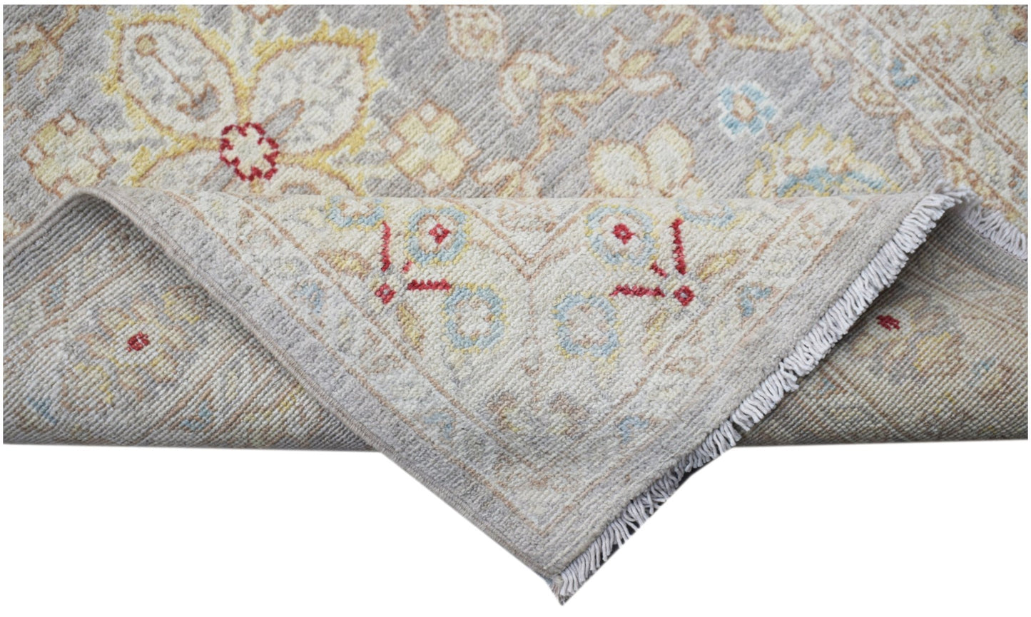 A corner of a handmade Afghan Chobi runner featuring a floral pattern in soft neutral tones.