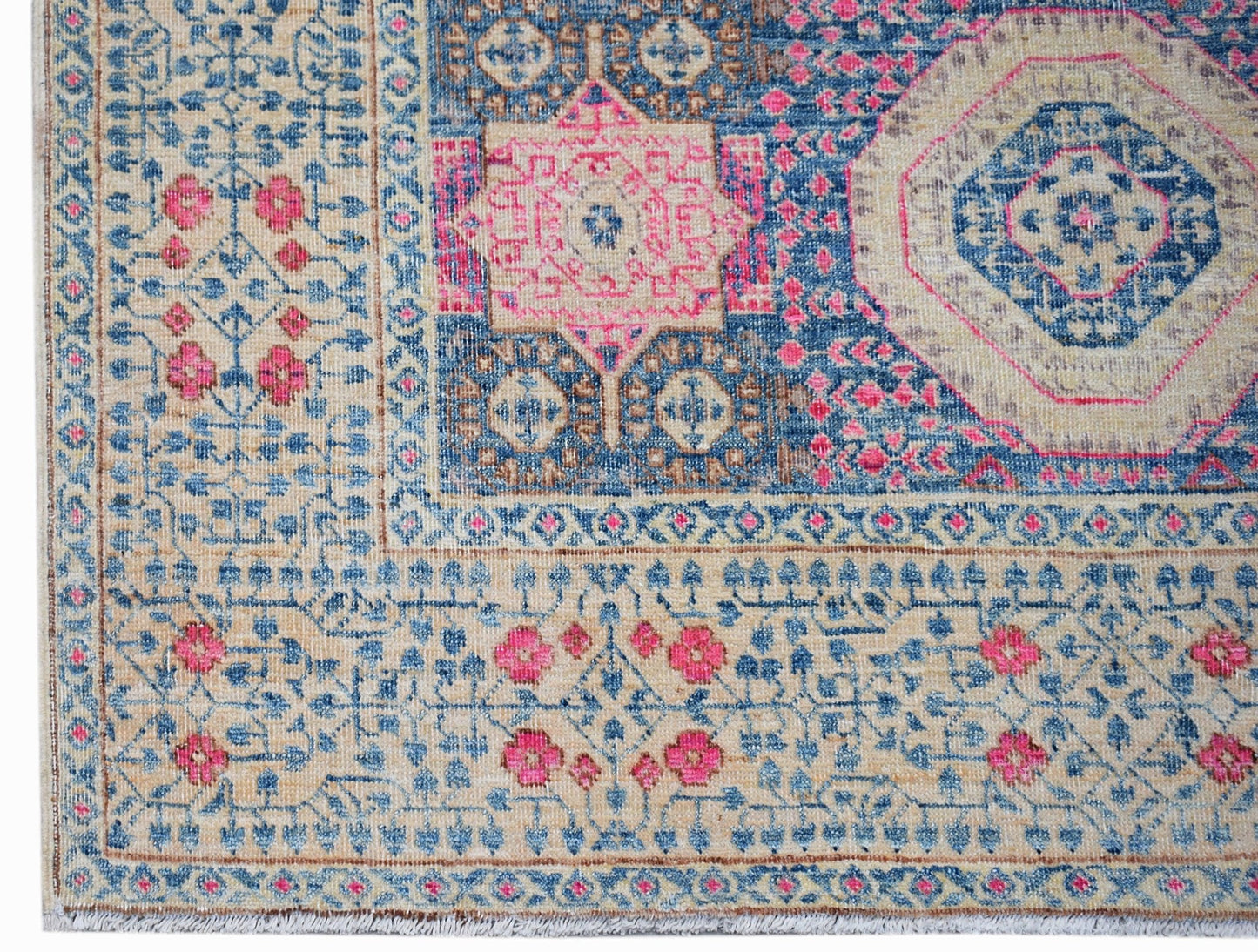 A handwoven Afghan Mamluk rug featuring a detailed geometric medallion in blue, pink, and beige.