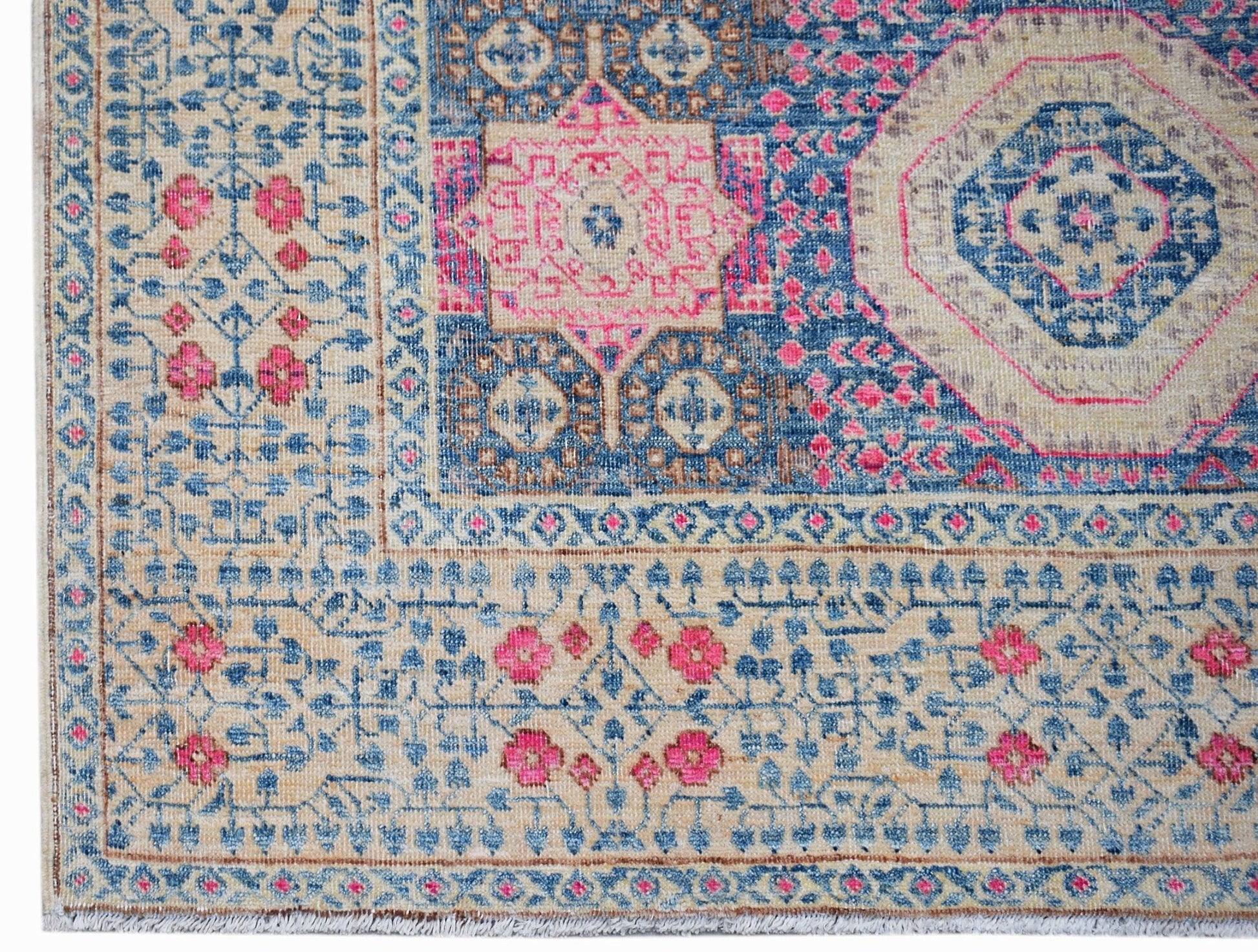 A handwoven Afghan Mamluk rug featuring a detailed geometric medallion in blue, pink, and beige.