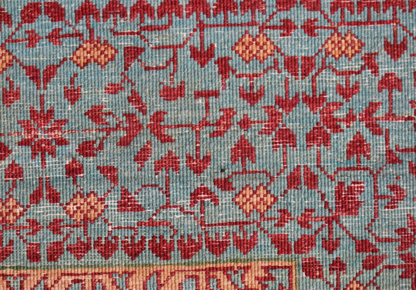 A close-up of a handwoven Afghan Chobi rug featuring a detailed red and orange Mamluk pattern.
