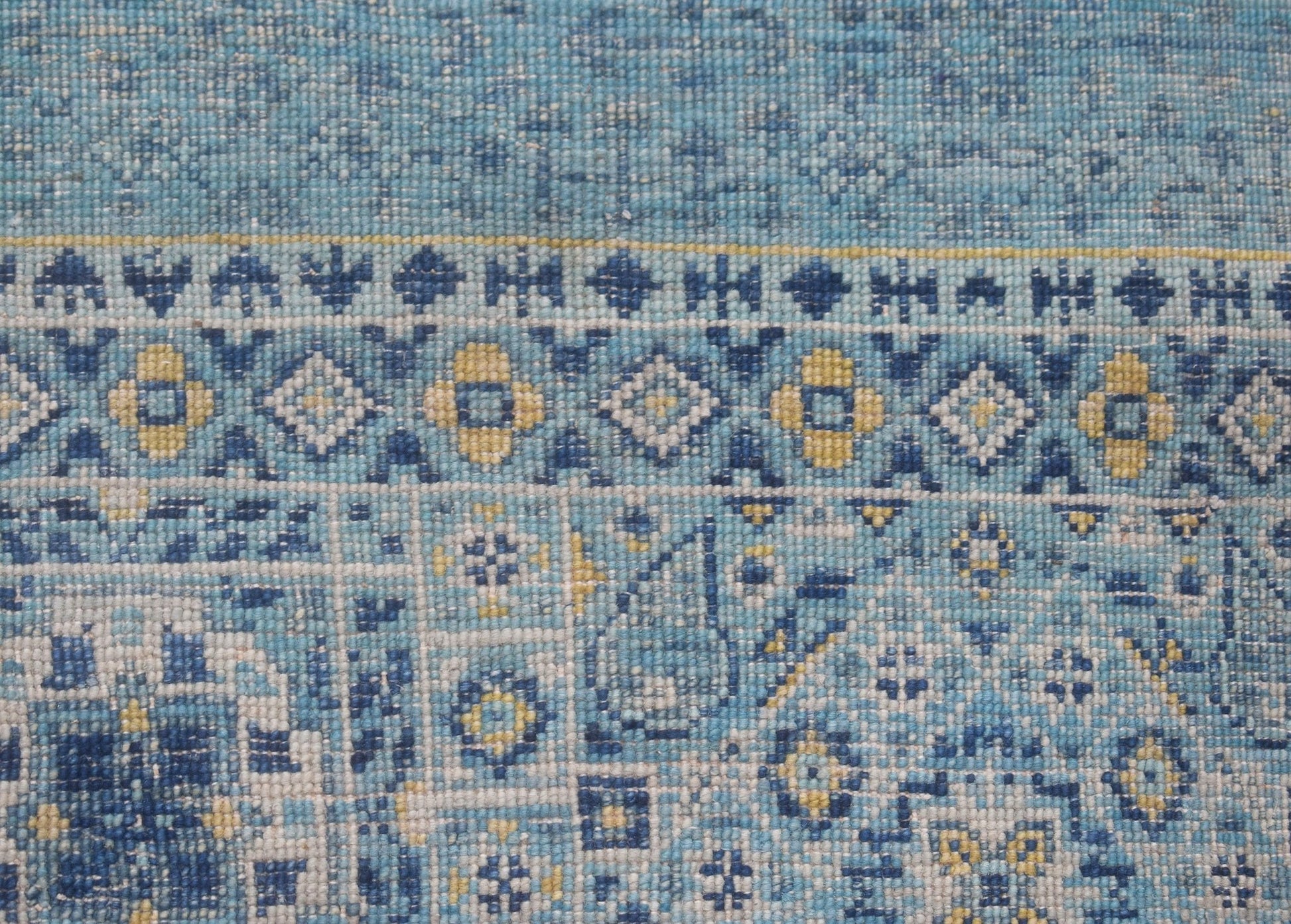 A close-up of a handmade Afghan Mamluk runner featuring intricate blue and yellow geometric motifs.