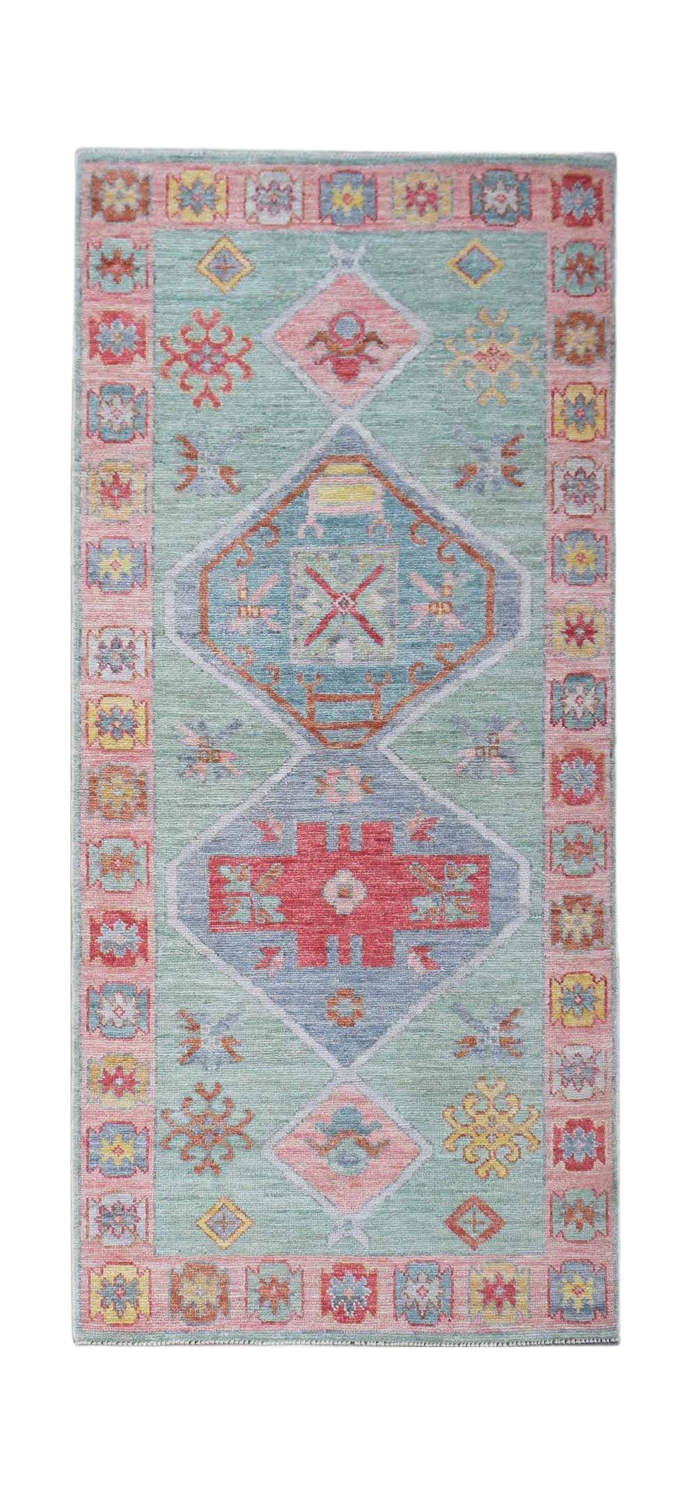 A handwoven wool runner rug featuring a light blue field with geometric patterns in pink and blue.