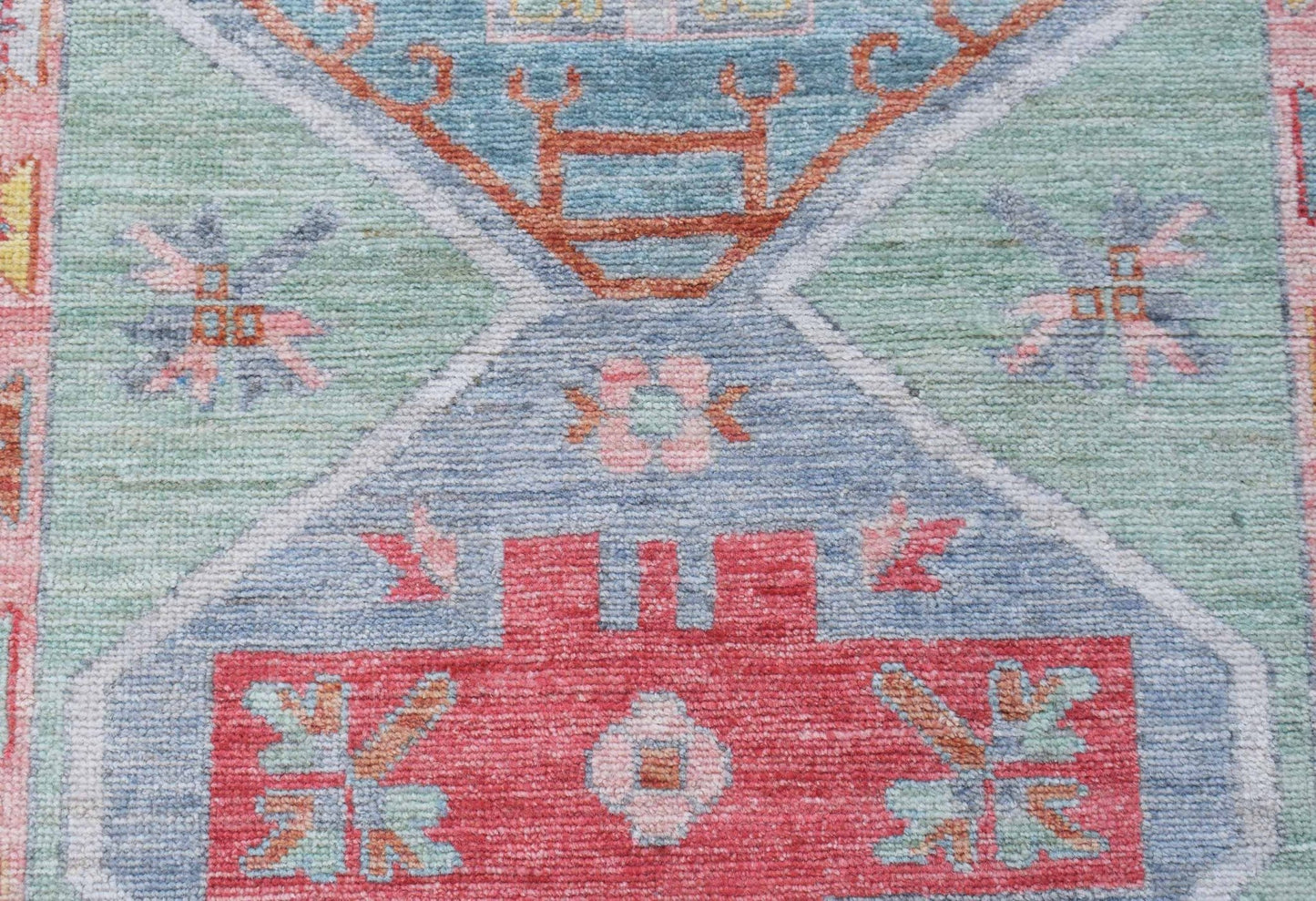 A handwoven wool runner featuring a transitional Oushak pattern in blue, green, and red tones.