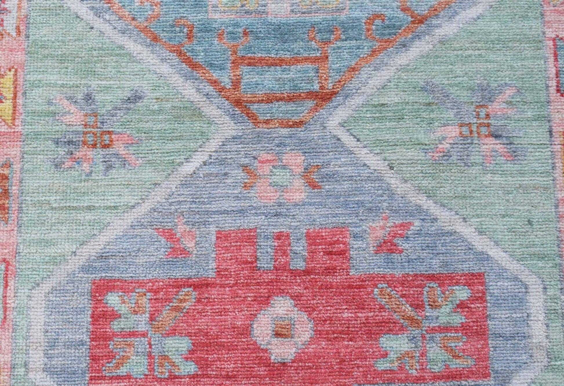 A handwoven wool runner featuring a transitional Oushak pattern in blue, green, and red tones.