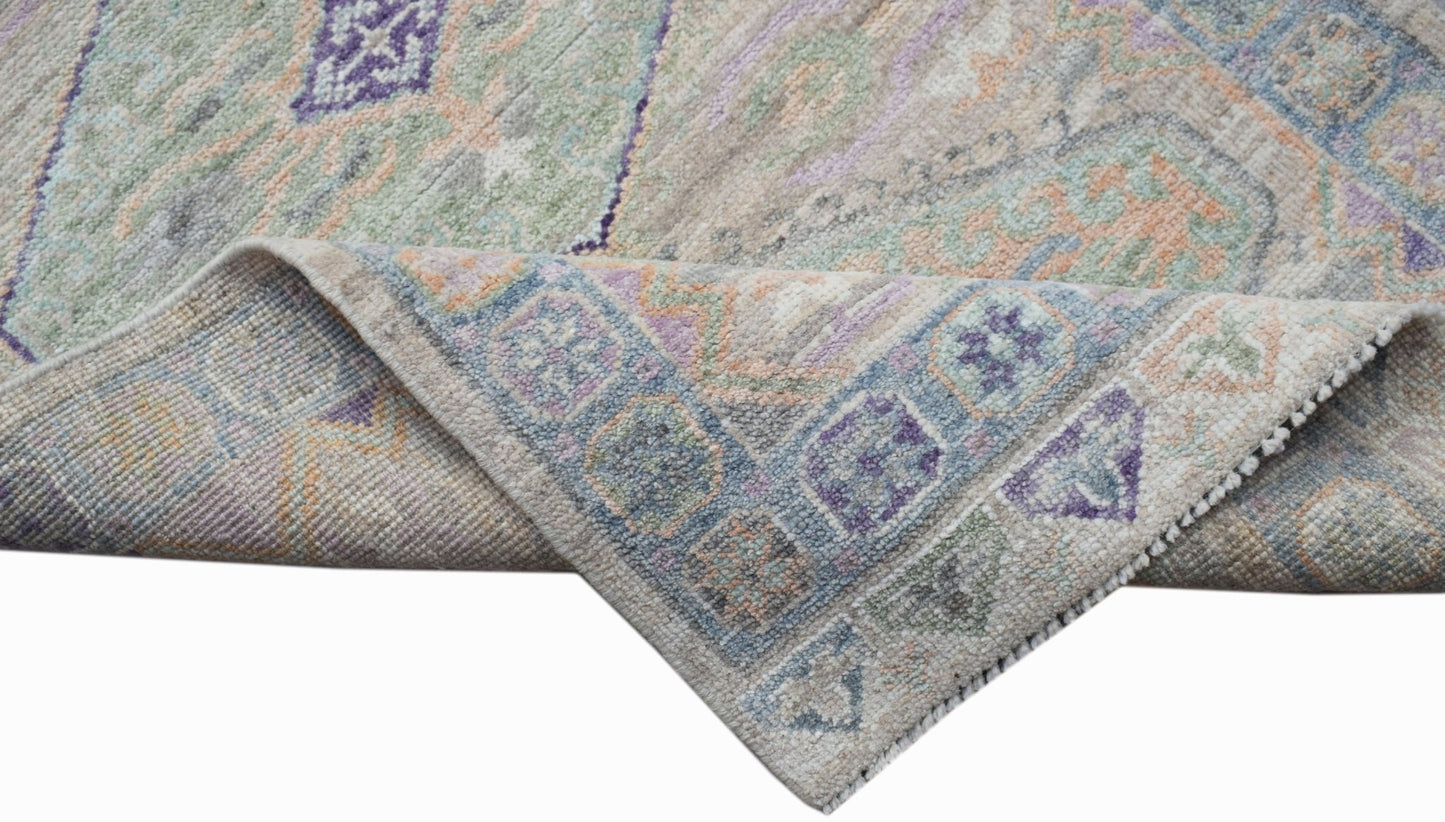 A handwoven wool runner rug featuring a transitional Oushak pattern in soft pastel tones.