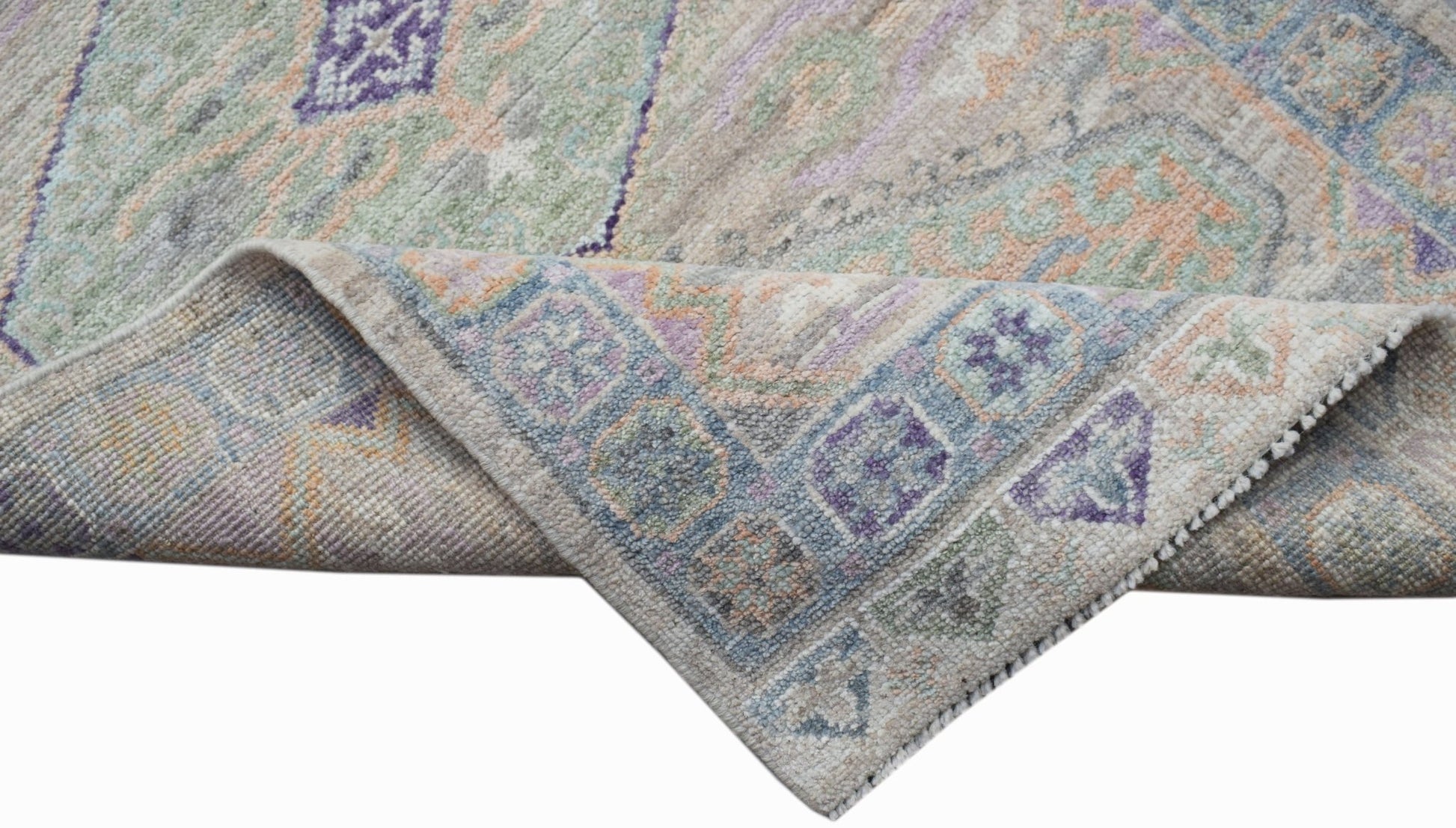 A handwoven wool runner rug featuring a transitional Oushak pattern in soft pastel tones.