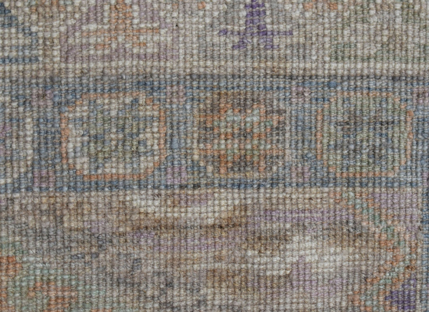 A close-up view of a handwoven wool runner featuring a transitional pattern in muted earth tones.