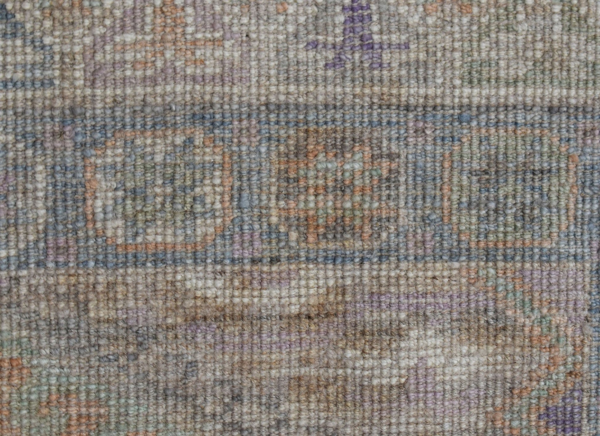 A close-up view of a handwoven wool runner featuring a transitional pattern in muted earth tones.