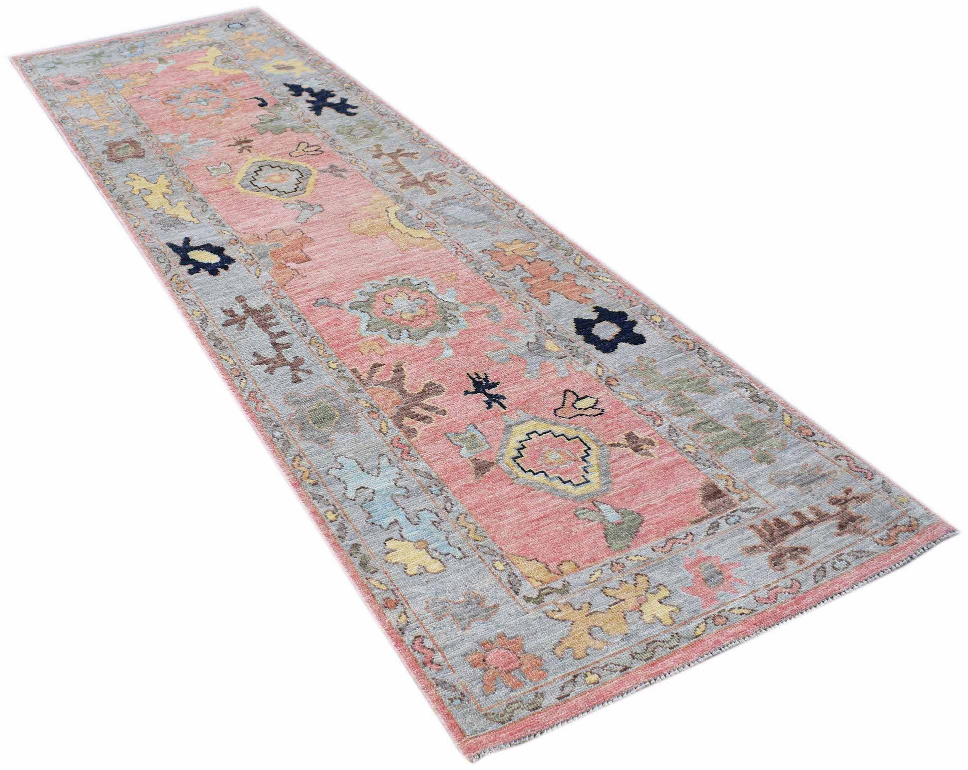 A handwoven transitional Oushak runner featuring a floral pattern in pink, blue, and yellow tones.
