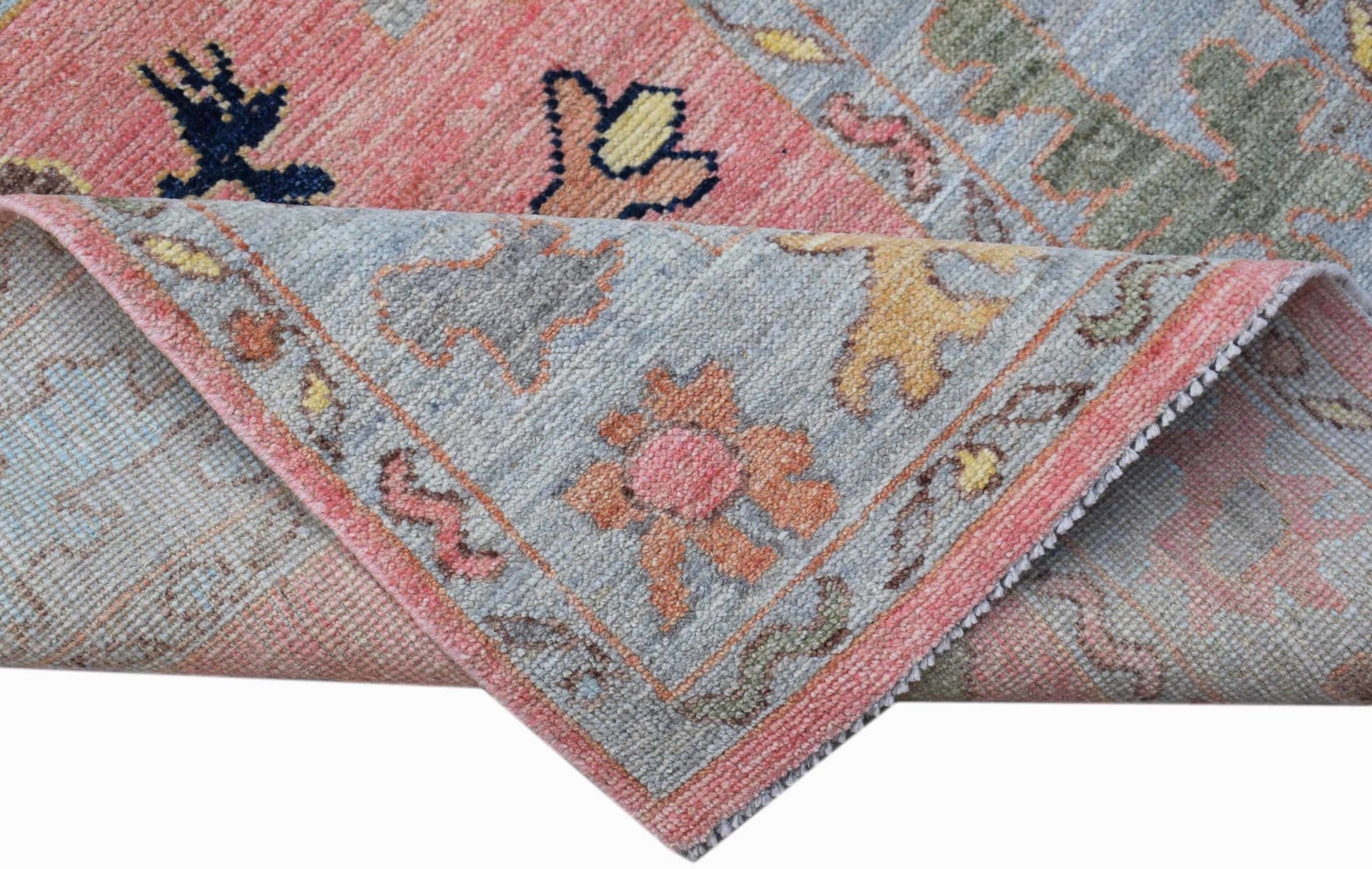 A handwoven wool runner rug featuring a floral pattern in soft pink, blue, and muted earth tones.