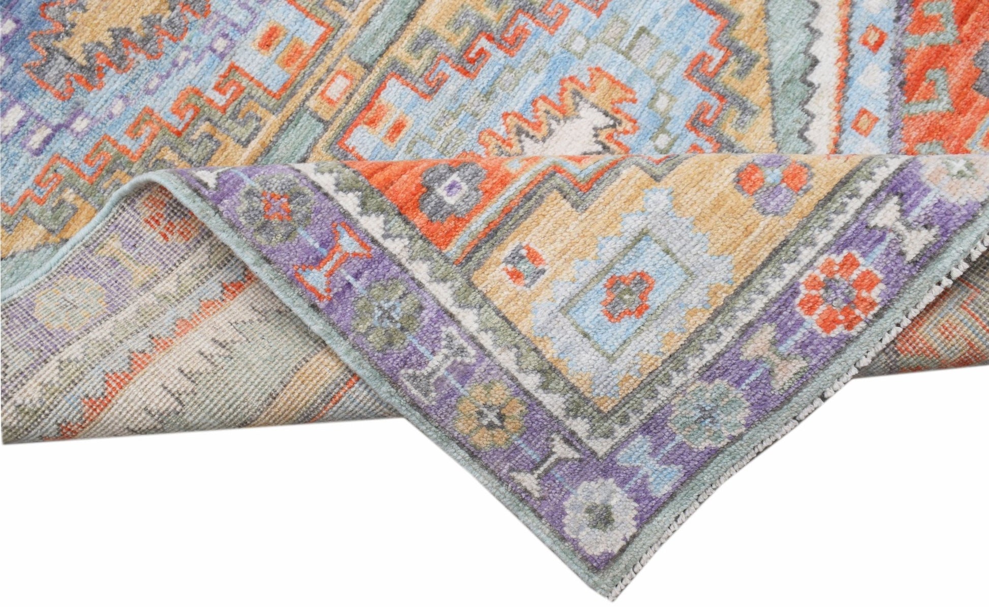 A handwoven transitional Oushak rug featuring a colorful geometric pattern in wool.