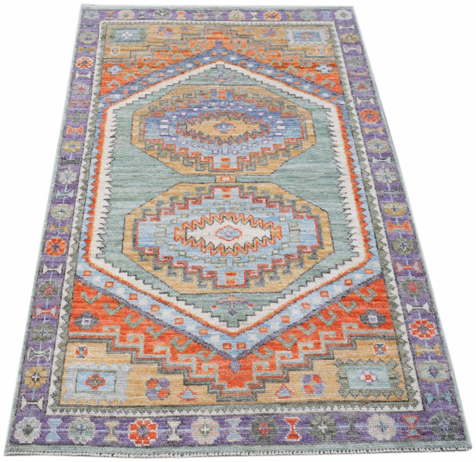 A handwoven transitional Oushak rug featuring geometric patterns in blue, orange, and purple.