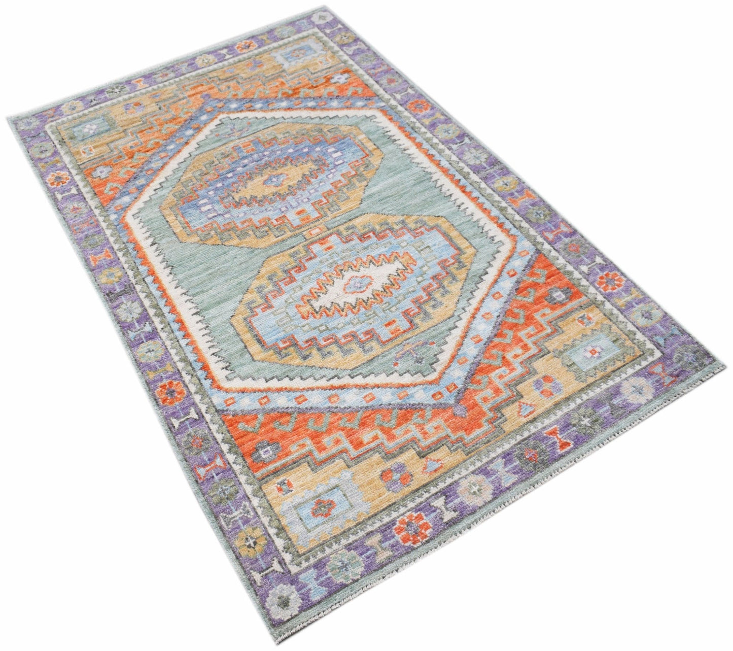 A handwoven transitional Oushak rug featuring a geometric pattern in blue, orange, and purple.