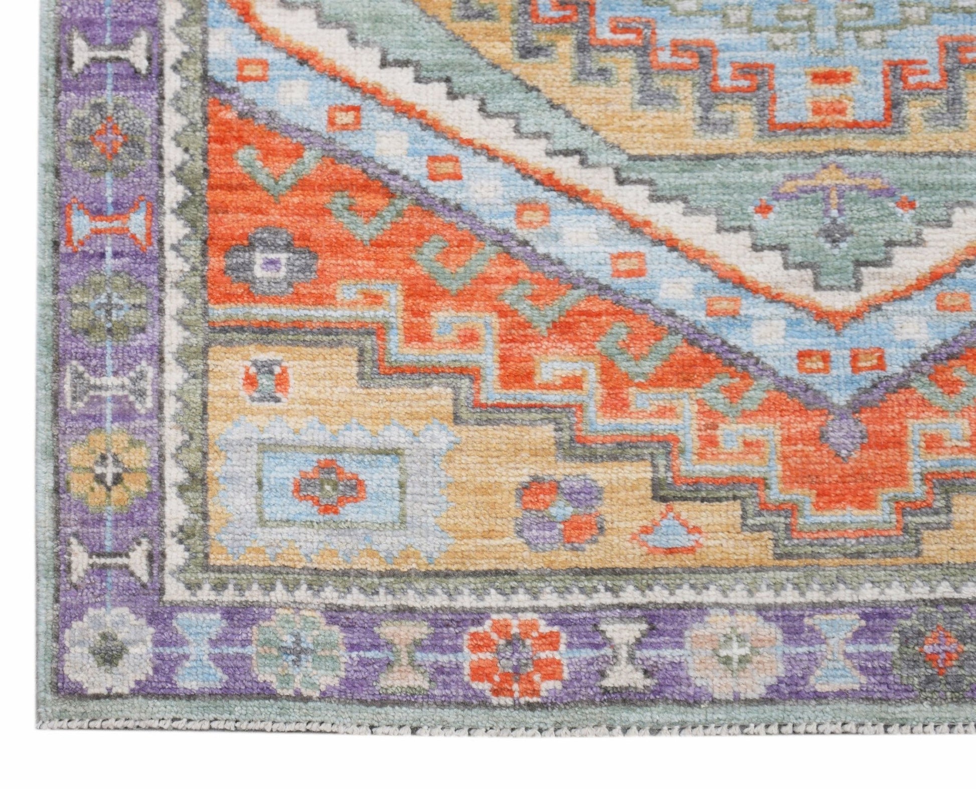 A handwoven transitional Oushak rug featuring a geometric pattern in vibrant orange, blue, and gold.